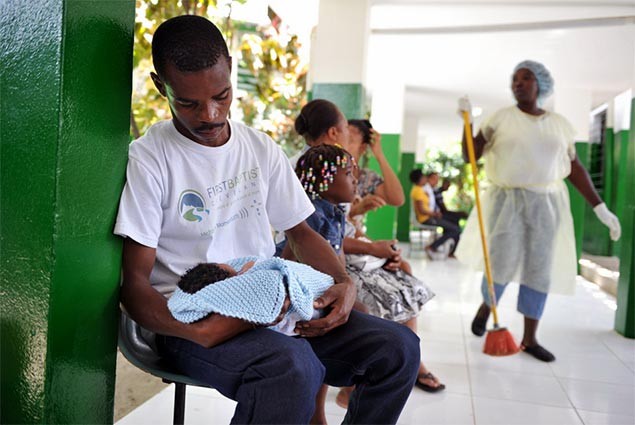 A father looks down at this newborn child in Haiti