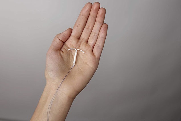 A hand holds an intrauterine contraceptive device