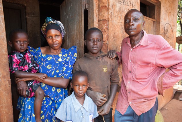 A husband, wife, and their three children stand in front of their home.