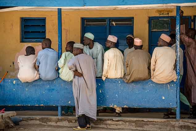  A group of men in Nigeria waiting for their wives outside a health clinic in Nigeria