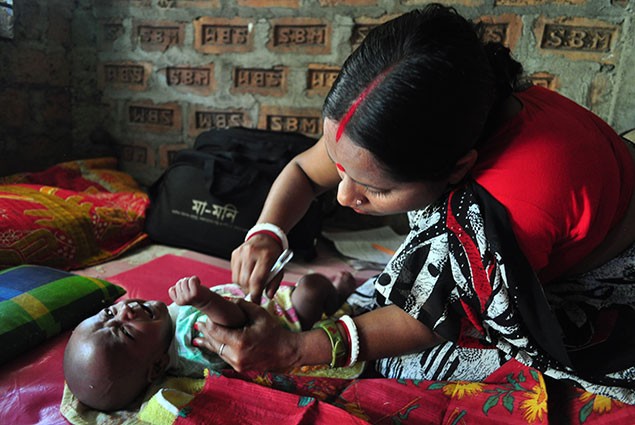 A community health worker examines a newborn baby.