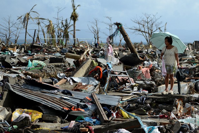 A surivor walks among the debris of houses destroyed by Super Typhoon Haiyan in Tacloban in the eastern Philippine island of Ley