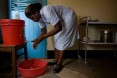 A woman washes her hands with water from a bucket with a spigot