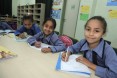 Young girls pause their writing lesson to smile for the camera at the opening of Khalwla Bint Al Azwar School in Mashare’a, Jord