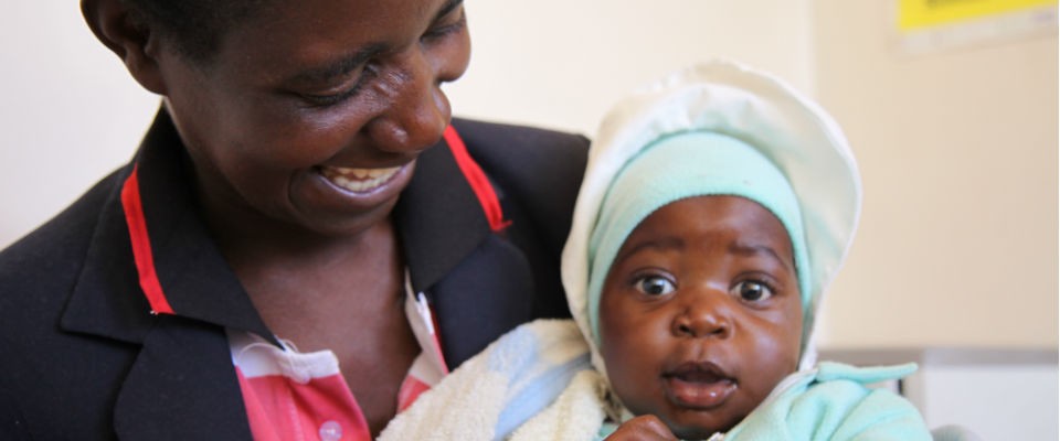 Rosemary proudly holds her HIV-free baby after receiving prenatal treatment from a USAID-sponsored clinic outside Harare, Zimbab