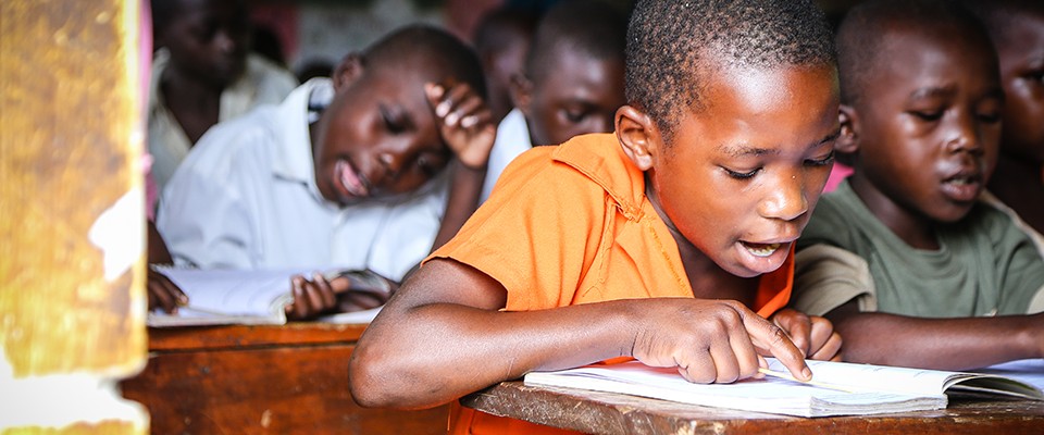 A pupil reads from a book provided by USAID.