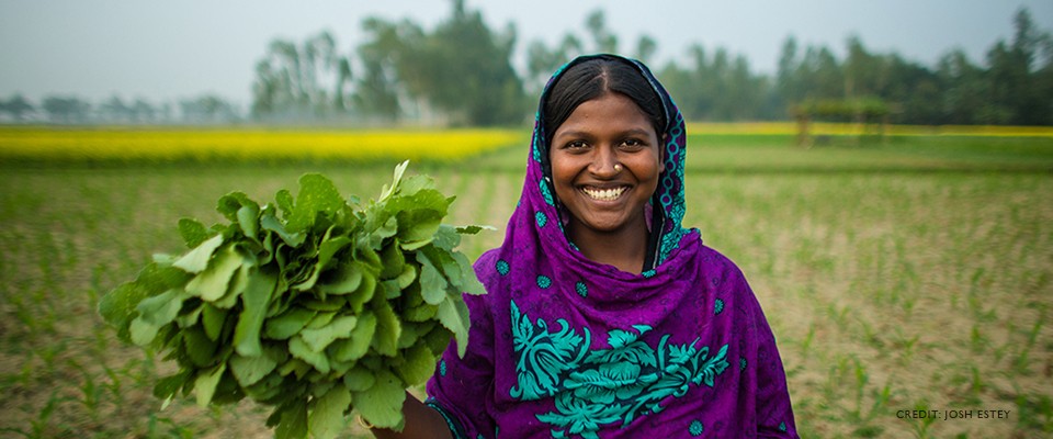 Image of Monjuara standing with vegetables in her hand.