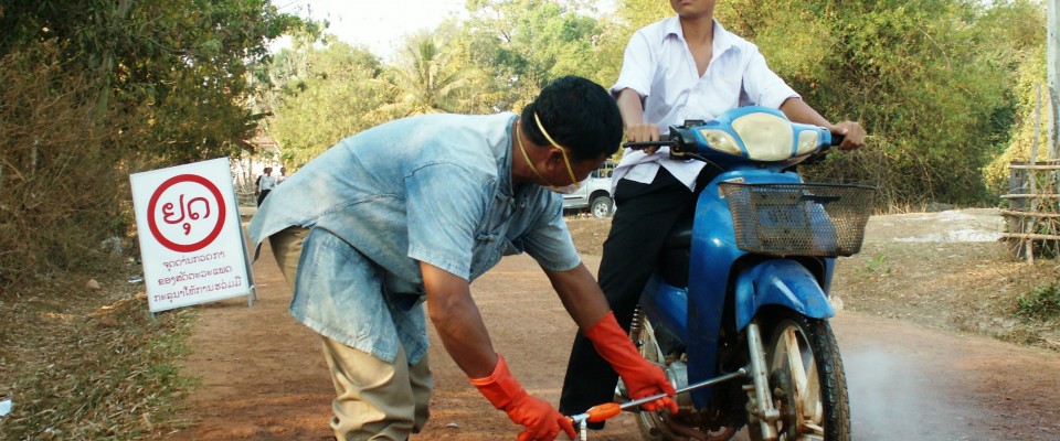 A health worker disinfects a motorcycle at a checkpoint during an avian influenza simulation exercise in Savanaket.  