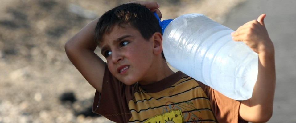 A young boy, a Syrian refugee, carries a container of water in Kilis, Turkey at the border with Syria.