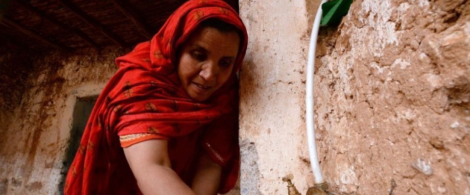 Woman beneficiary collecting water from a newly installed faucet in her village