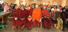 Monks sit among a group of people waiting to remove their bandages following cataract surgery.