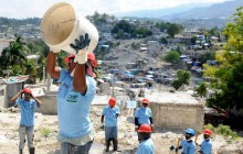 A woman catches a bucket in a line for rubble removal in the hilly Ravine Pintade neighborhood in Port-au-Prince, Haiti, Feb. 16