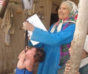 A community health worker checks a child’s weight gain during a growth monitoring session in Jawzjan Province.