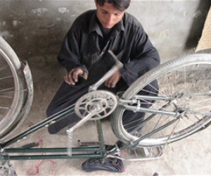 Ashraf Khan fixes a bicycle in his shop, which he opened after completing a USAID-funded bicycle repair course. The shop provide