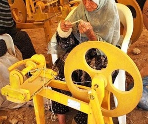An Afghan woman uses a foot-treadle spinning wheel that has boosted her productivity and helped to provide jobs for other local 