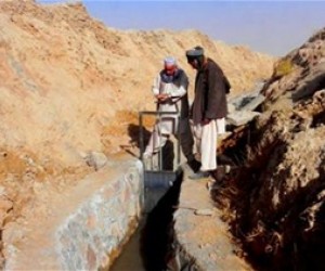 Members of the community in Shindand District in Herat Province watches as the karez is closed. This stops the water from flowin