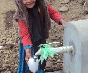 A new piped water system fulfills a basic need for residents. Here a young girl collects a glass of drinking water from newly co