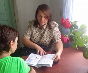A nurse consults with a client using a 'patient's diary,' a booklet developed by USAID that tracks TB treatment progress.