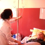 Një infermiere po i ben një serum një pacienti
