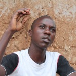 A young Kenyan man sitting in front of a wall 