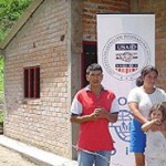 Flor and José Baca pose in front of their new home in Los Andes de Sotomayor, Nariño, which USAID helped them build with their o