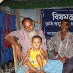 Bangladeshi farmer Nazrul Islam Khan, with his grandson on his lap, made a profit on his crops after using a melon fly trap that