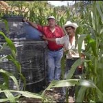 José Pérez (right) shows visitors the water storage tank he installed on his farm.