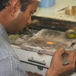 An artisan in a Karachi workshop solders gold bangles with a gas flame.