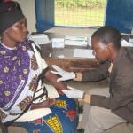 Government health worker Frank Mputa prepares to collect a blood sample from a local woman during a voluntary counseling and tes