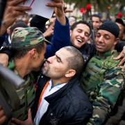 Tunisian protesters kiss soldiers during a demonstration against the presence of the toppled ruling party in the transitional go
