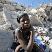 A Haitian woman rests on the rubble of a destroyed building at a market in Port-au-Prince following a massive 7.0-magnitude quak