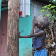 A Haitian boy inspects the installation of an early-stage microgrid meter box.