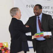 USAID Ethiopia Mission Director Dennis Weller (left) presents some of the new mother tongue reading materials to Minister of Edu