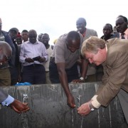 USAID and Government of Kenya representatives wash their hands using an outdoor faucet