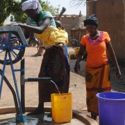 Women gathering water from a well improved by the USAID West Africa Water Supply, Sanitation and Hygiene Program  