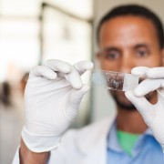 A HEAL TB-trained laboratory technician at the Lich Health Center in the Amhara Region examines a slide with sputum smear. The s
