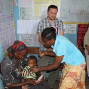 Ambassador Haslach observing a malnourished child being examined by a health extension worker at the health post.