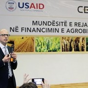 A man with a microphone delivers remarks on a stage