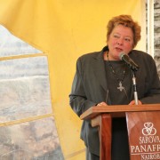 A woman stands behind a podium and speaks to an audience