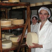 A man holds a block of cheese in a cheese storage facility