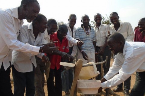 The men of the Asisizaneni Community Health Club demonstrate how to use a tippy tap for hand washing.