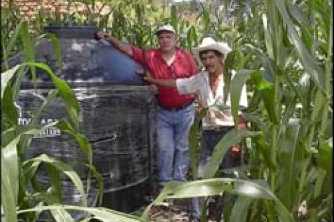 José Pérez (right) shows visitors the water storage tank he installed on his farm.