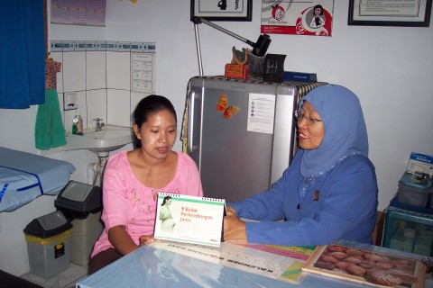A mother of two, Rubeha Purwanto (left) confers with her community nurse/midwife, Erna Genasih, in West Jakarta